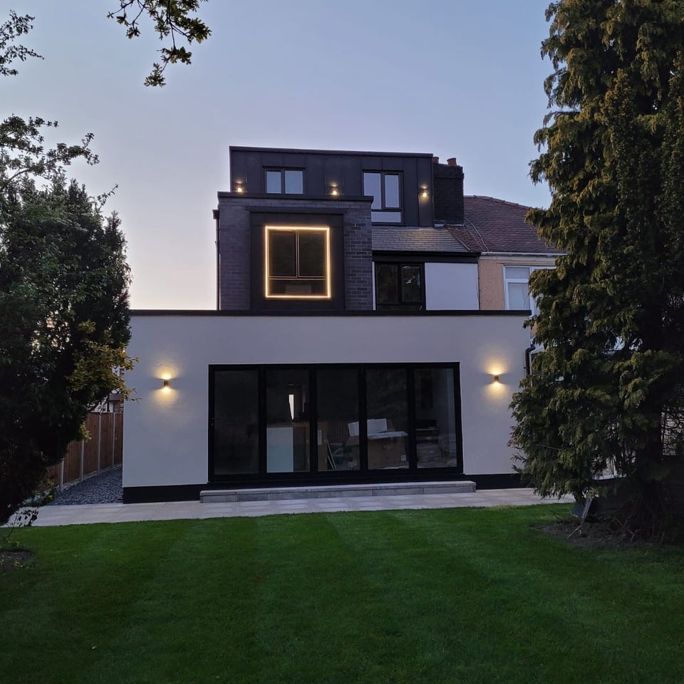 the exterior of a modern home at dusk with Standing Seam cladding 
